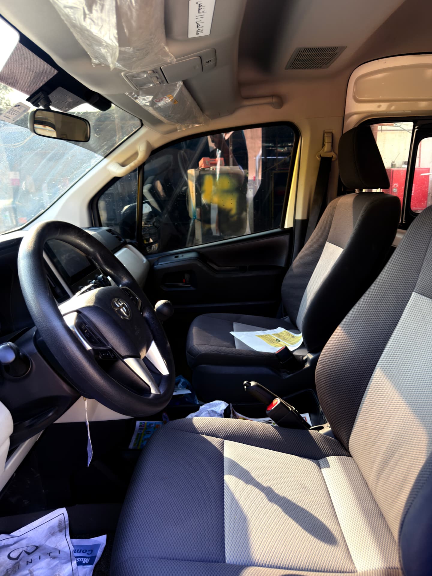 Front cabin of Toyota Hiace van showing driver and passenger seats, air-conditioned interior