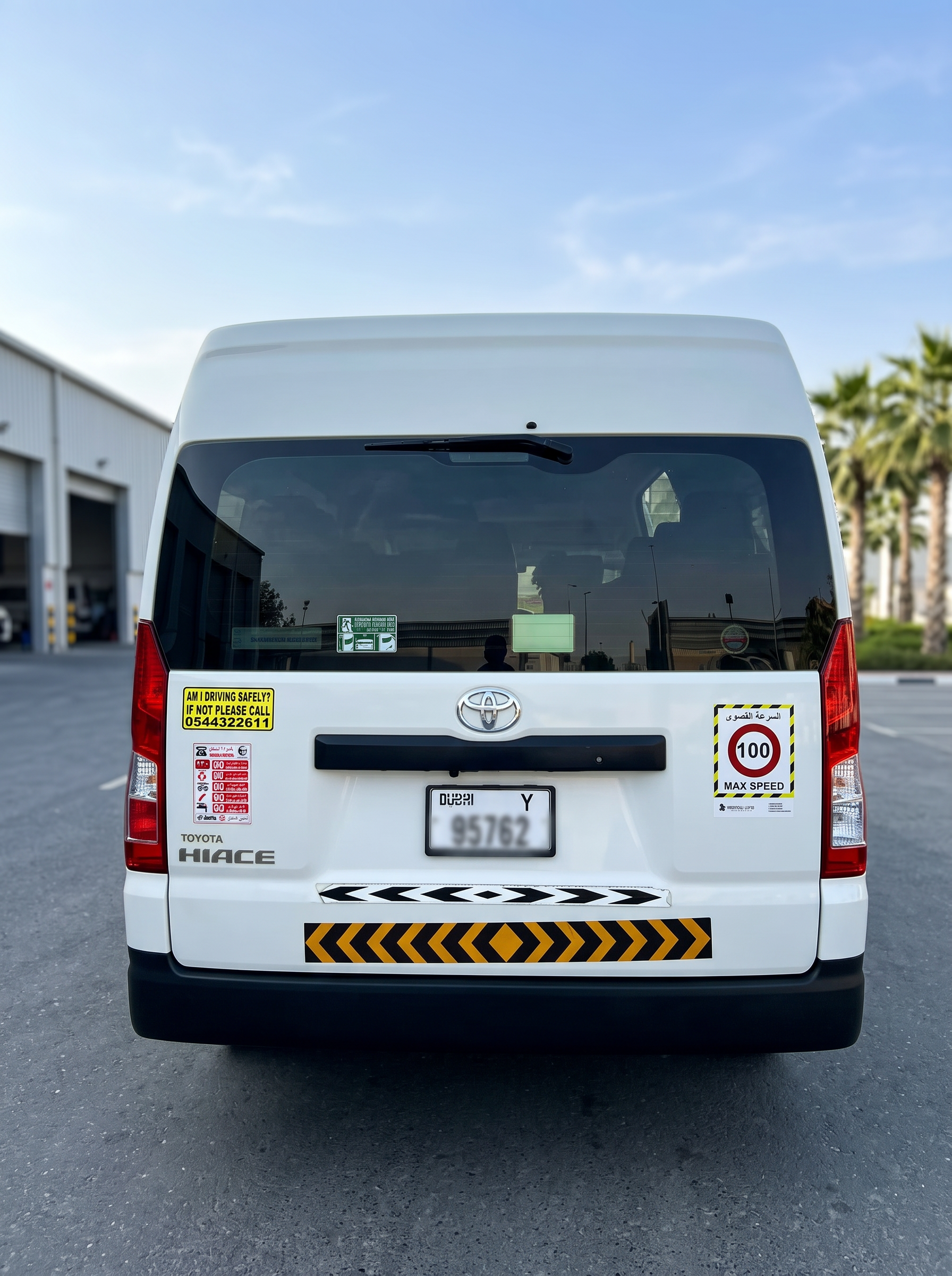 Rear of Toyota Hiace rental van showing RTA safety stickers and chevron strip, UAE compliant